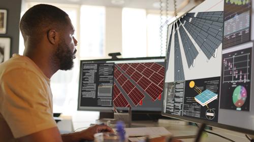 person looking at engineering software programs on dual monitor computer.